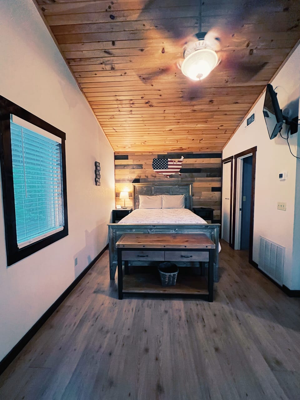 Your cozy bedroom features rustic wood plank accents, a comfortable bed with crisp linens, and warm lighting that creates the perfect retreat after a day of exploring.