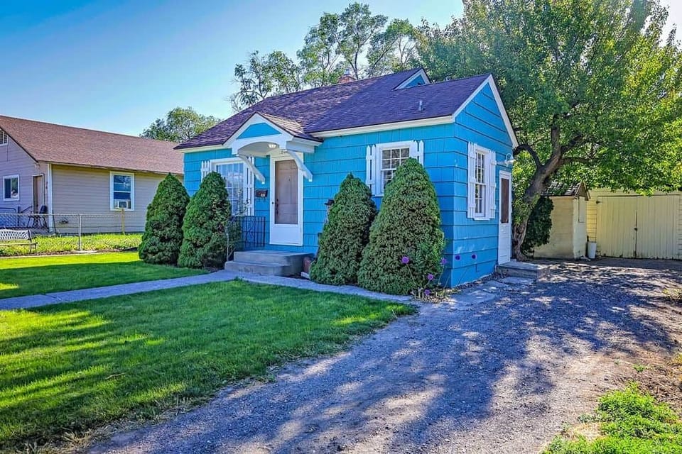 Cozy blue cottage with private driveway, mature trees, and classic curb appeal