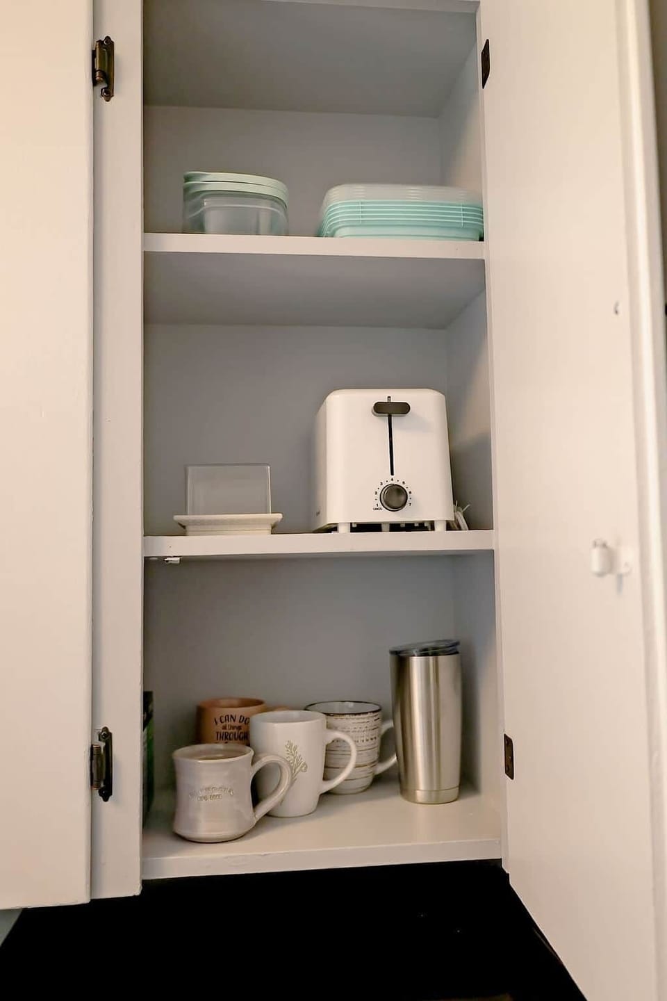 Cabinet stocked with toaster, storage containers, and a variety of coffee mugs