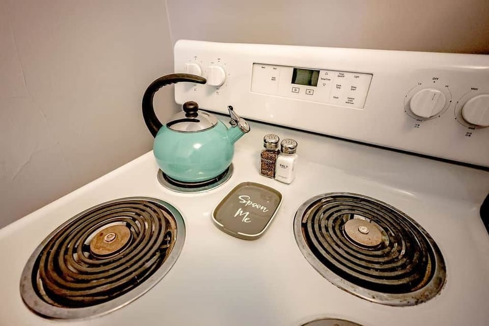 Cute stovetop detail with teal kettle, salt and pepper, and a “Spoon Me” spoon rest