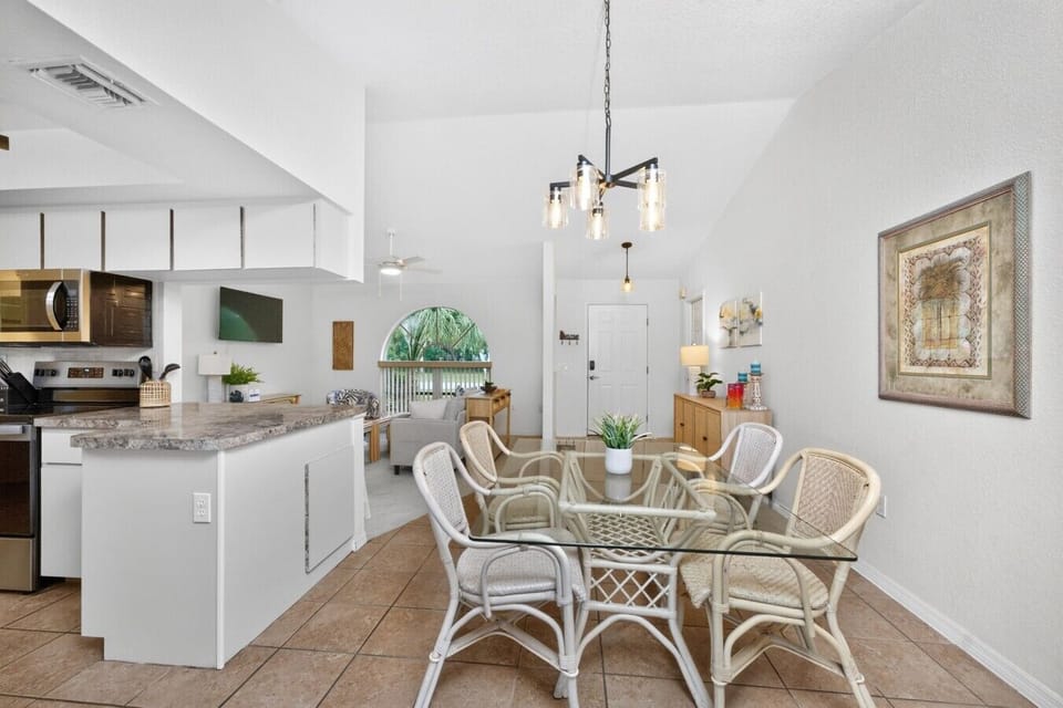 Gather around the dining table for six in this bright open-concept space featuring a breakfast bar, fully equipped kitchen, and easy access to the screened lanai and private pool—ideal for family meals and entertaining.
