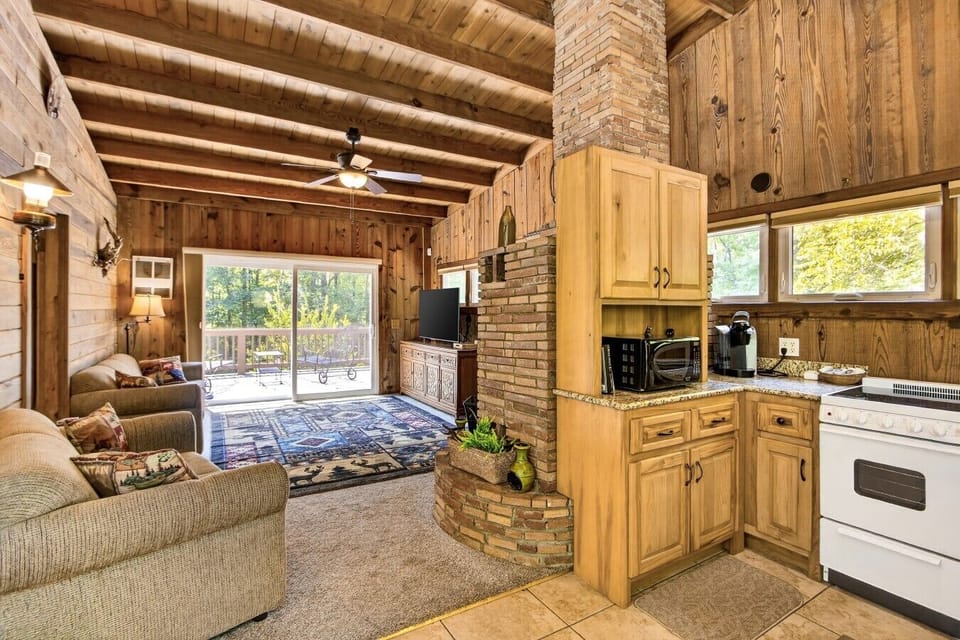 Living room and kitchen share one open space, with two sofas, a TV, and deck access through the sliding doors.