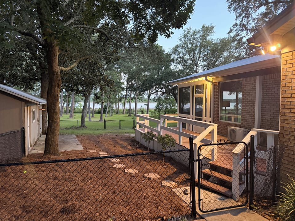 Fenced yard, shaded deck, and peaceful lake views through the trees