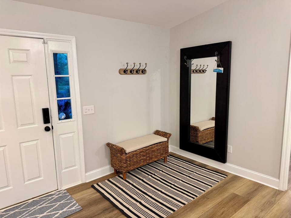 Bright, welcoming entryway with bench, hooks, and full-length mirror