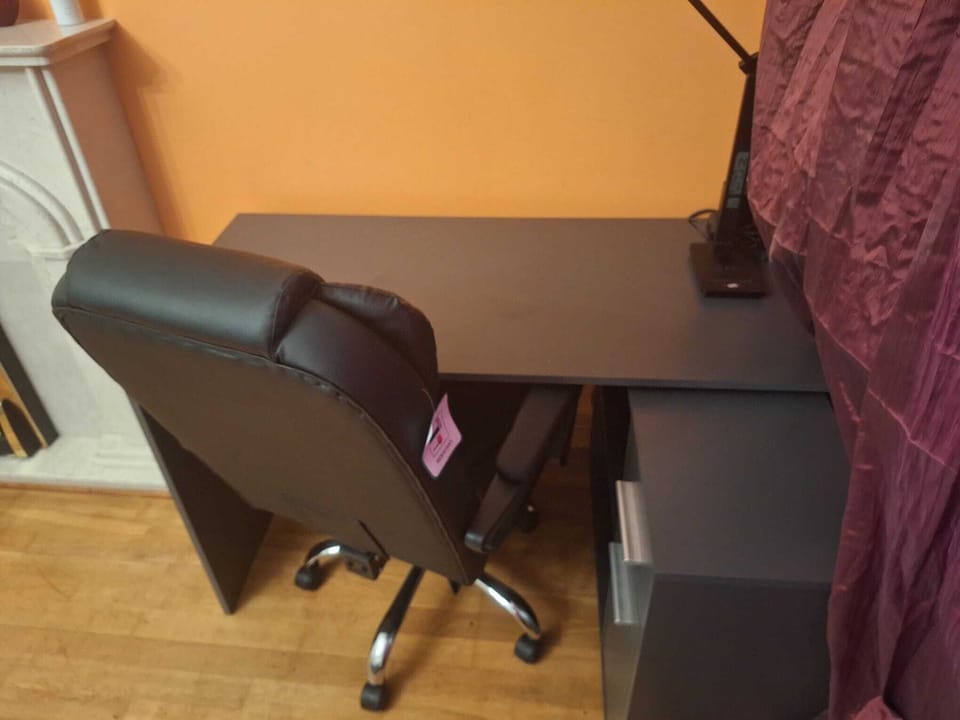 Work station. Big desk with ergonomic  chair, table lamp, wireless phone charger