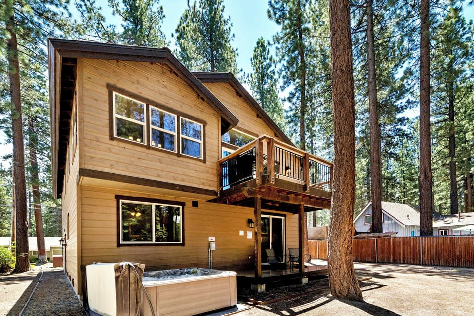 A charming two-story wood cabin nestled among towering pines, featuring a private hot tub and upper-level deck—your perfect mountain retreat.