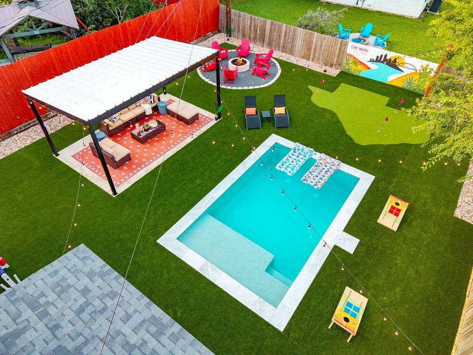 🌴 The ultimate Austin backyard from above: private pool, fire pit lounge, shaded pergola, putting green, and cornhole — all in one. 🔥⛳ String lights set the mood after dark, with our "Stay Weird" mural keeping it true to SoCo. 🌟