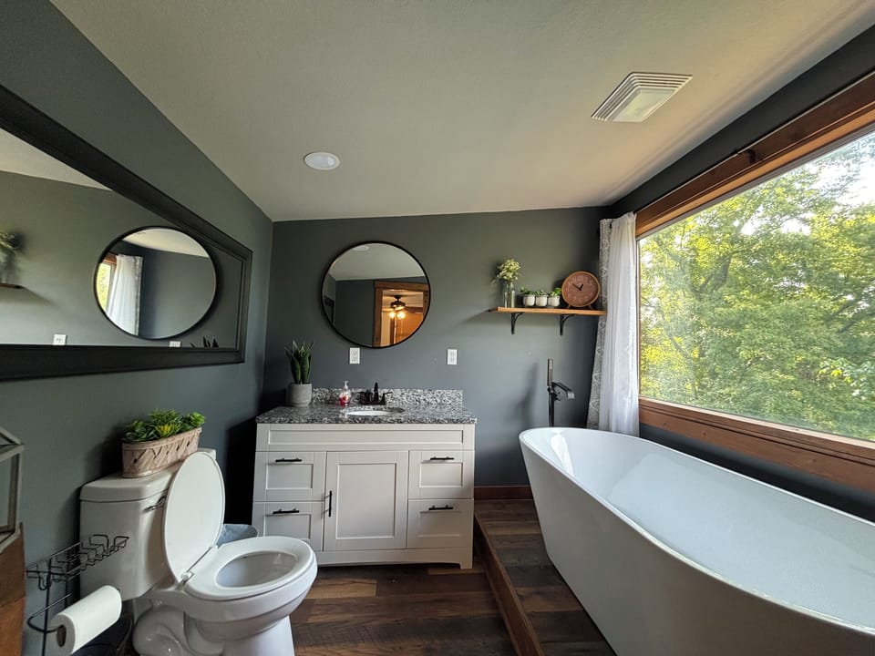 Spa-like bathroom with soaking tub and serene treetop views