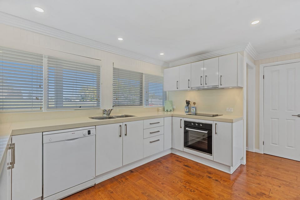 Bright modern kitchen with white cabinetry and warm wood floors