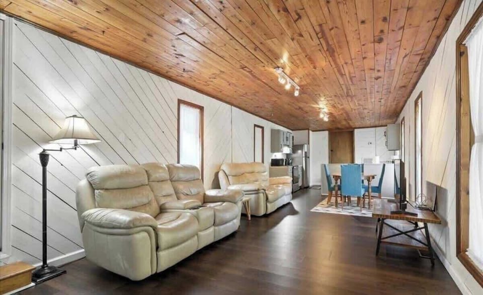 Relax in Backbeat Bungalow's spacious open-concept living room featuring two plush reclining leather sofas, Smart TV, warm wood ceilings, and plenty of space to gather after exploring Knoxville, Dollywood, Gatlinburg, and the Smokies.