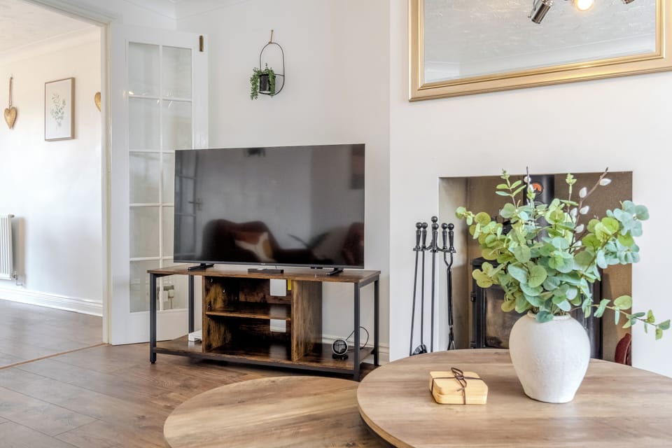 Bright, cozy lounge with fireplace, smart TV, and warm natural touches