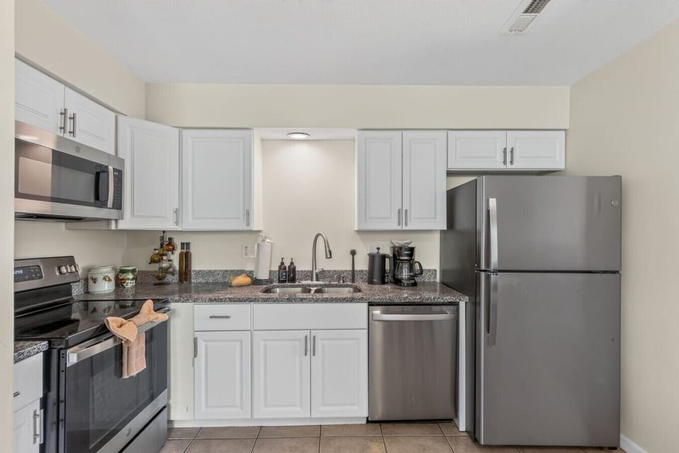 Fully equipped kitchen with stainless appliances, generous cabinetry, granite counters, and coffee essentials.