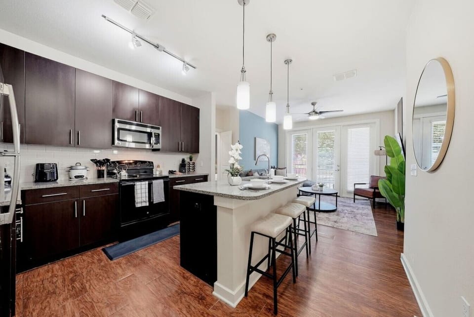 Sleek kitchen w/ dark cabinetry, granite counters & pendant lighting over the bar