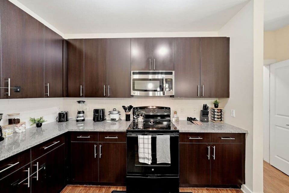 Dark wood kitchen cabinetry w/ stainless steel appliances & tile backsplash