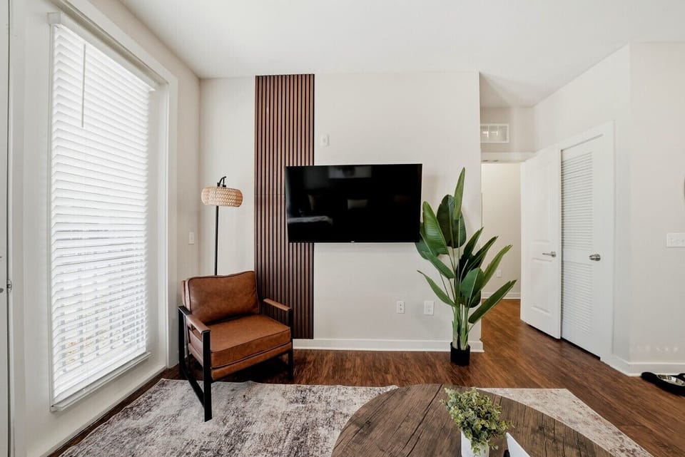 Cozy reading nook w/ leather chair, floor lamp & wall-mounted TV.