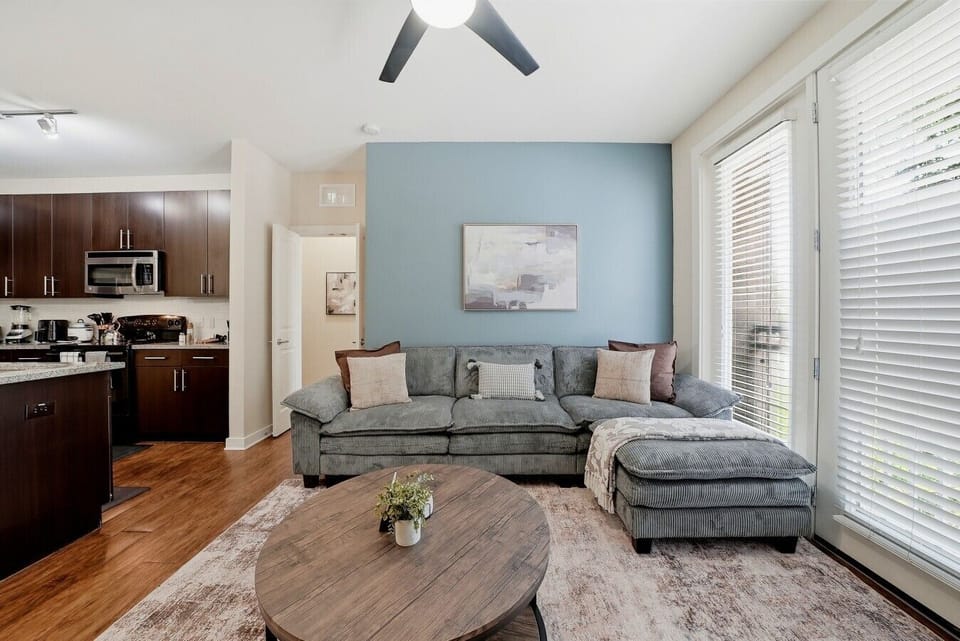 Spacious living room w/ sectional sofa, wooden coffee table & calming blue accent wall.