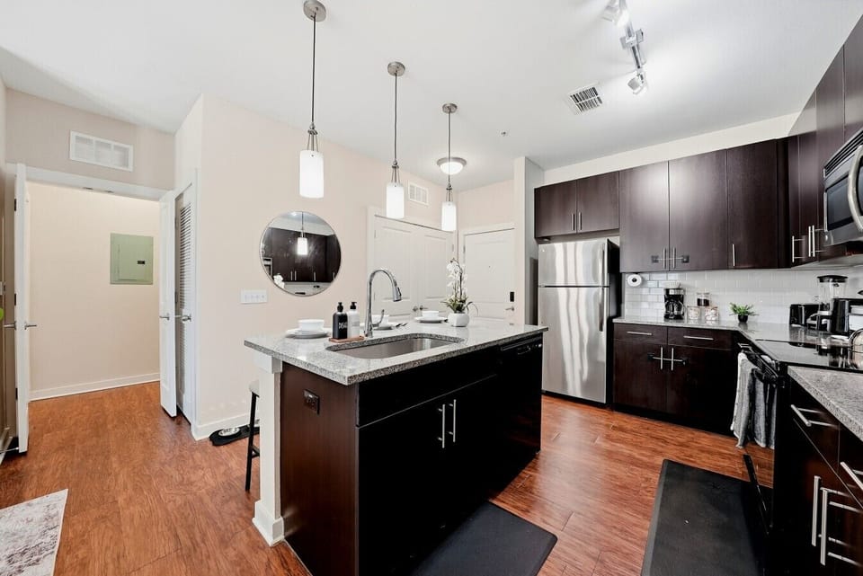 Modern kitchen w/ pendant lighting, granite counters & stainless steel appliances.