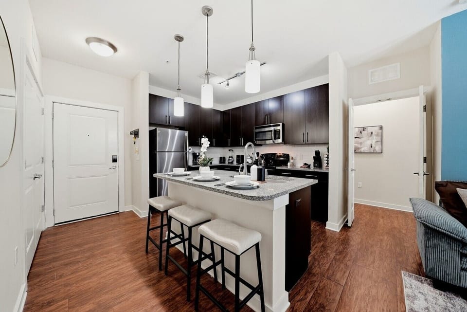 Sleek kitchen w/ dark cabinetry, quartz island & bar seating for 3.