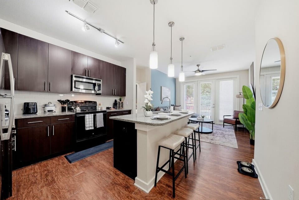 Open-concept kitchen w/ dark cabinetry, island seating & pendant lighting.