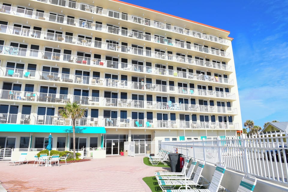 Beachfront property with private balconies, relaxing lounge areas, and palm trees welcoming you to your coastal retreat.
