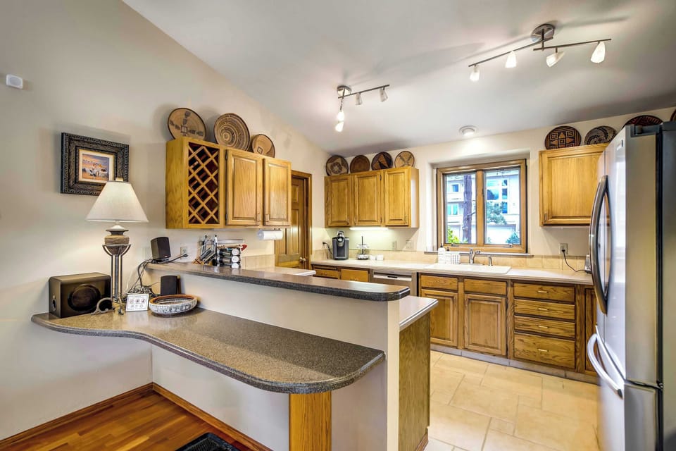 Rich oak cabinetry lines the kitchen, complete with built-in wine storage and tile flooring, offering ample storage for a fully stocked kitchen setup.
