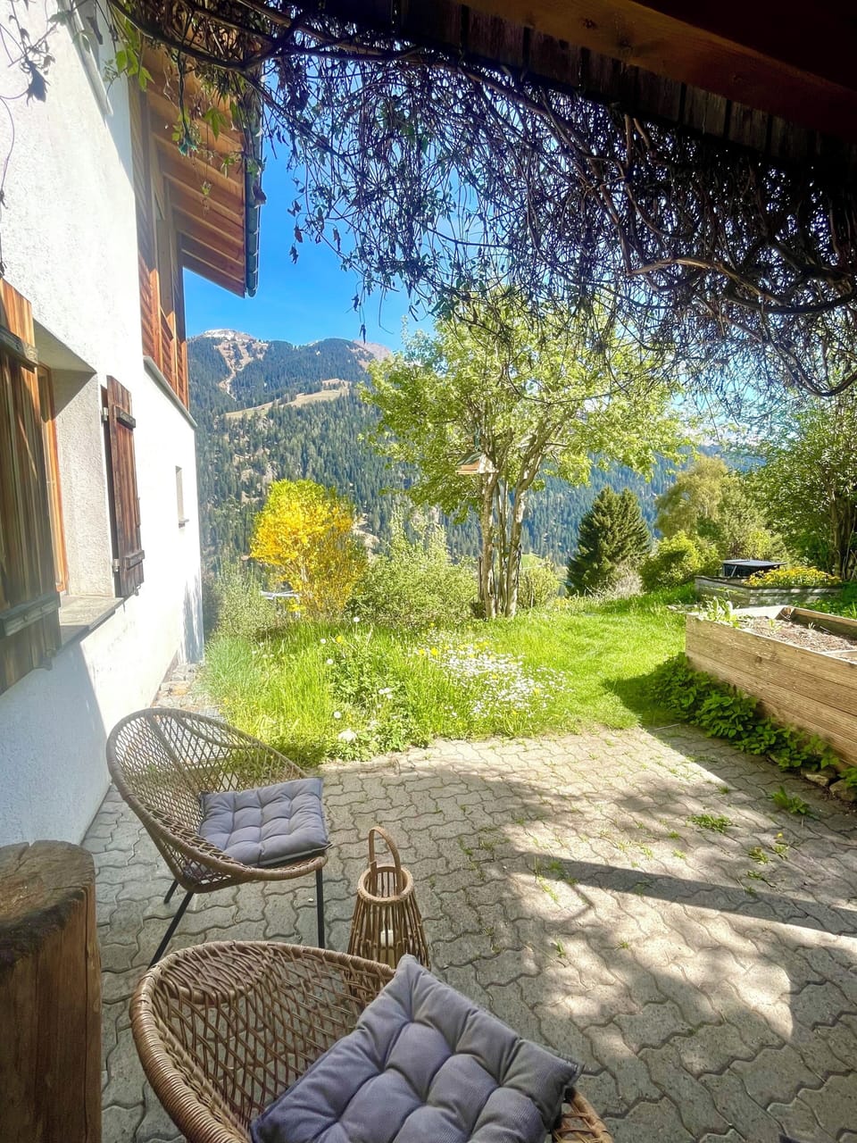 Sunny patio with cozy seating and serene mountain garden views