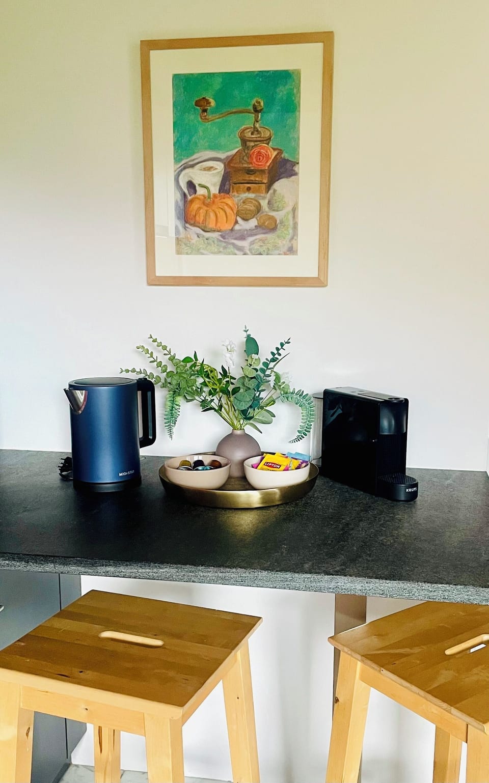 Welcoming coffee station with snacks, art, and cozy breakfast-bar seating