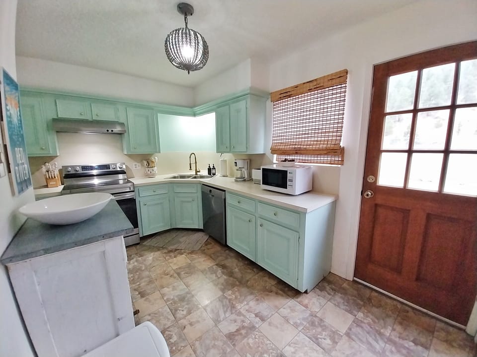 Your fully equipped kitchen awaits with charming mint-green cabinetry, modern appliances, and ample counter space—perfect for preparing your favorite meals at home.