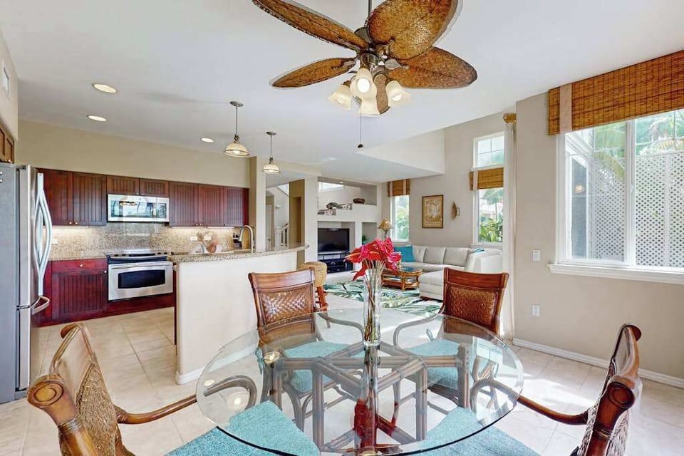 Dining room showcases comfortable seating ceiling fan and tropical artwork