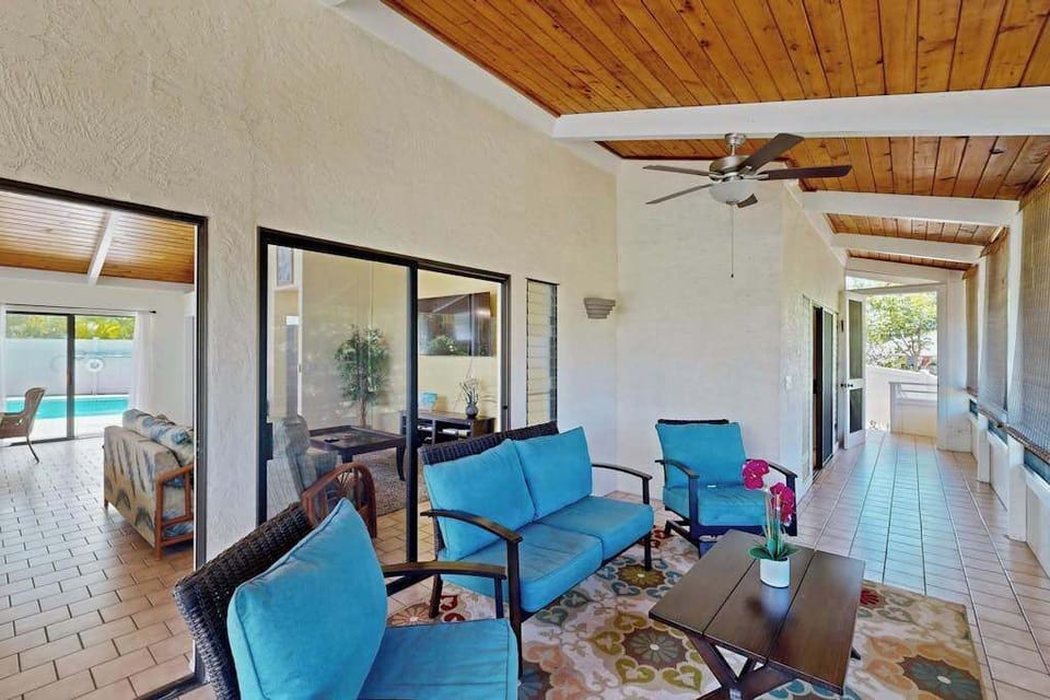 Covered living area opens onto balcony seating with ceiling fan