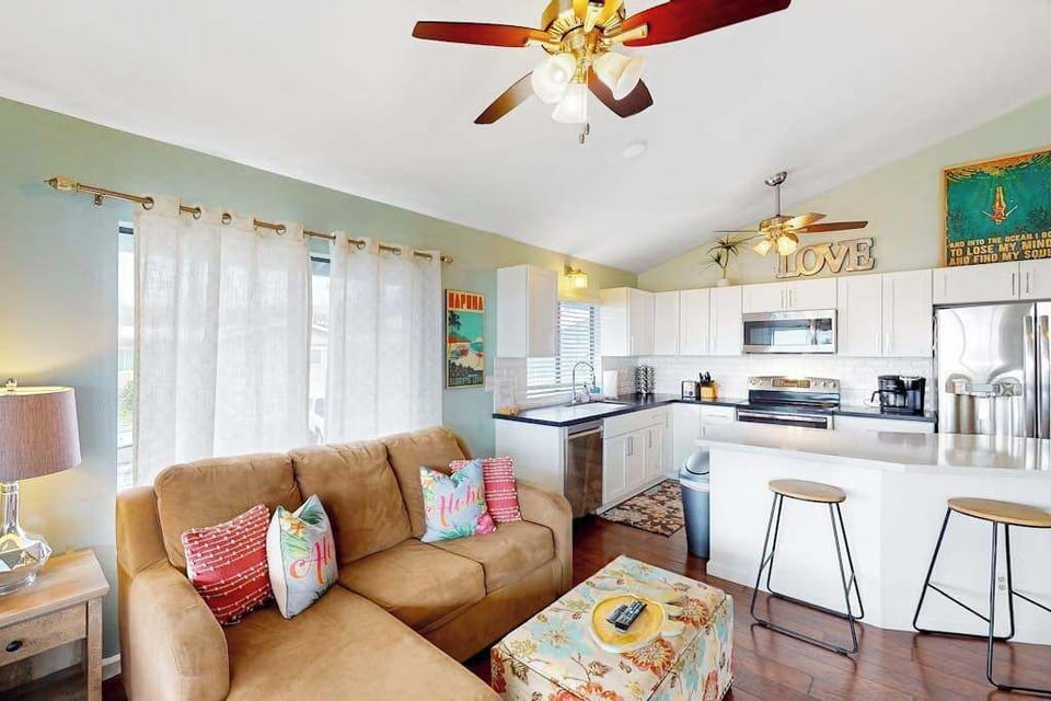 Bright open-concept living room and kitchen layout featuring a cozy sectional sofa, breakfast bar seating, and full appliances! 🛋️✨