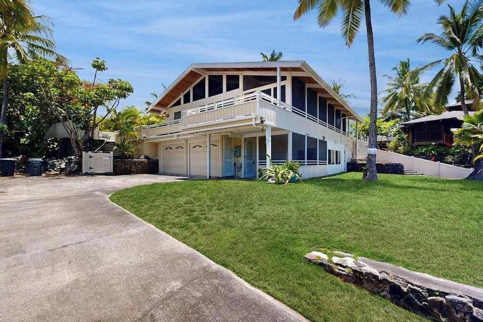 Front lawn and driveway frame the home with tropical landscaping