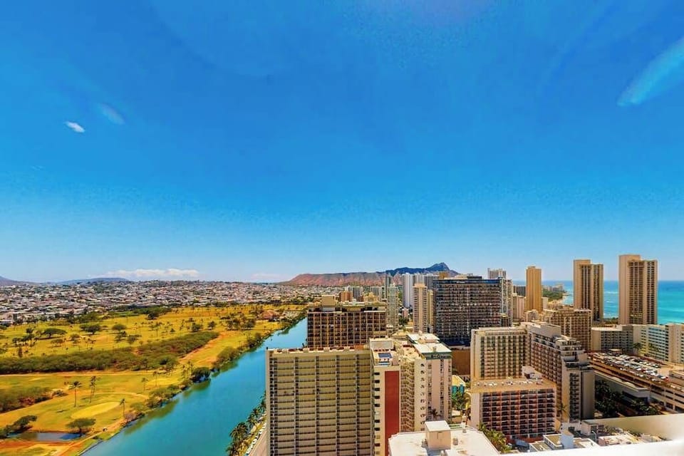 High-angle vantage point showcasing the turquoise Ala Wai Canal, the Ala Wai Golf Course, Diamond Head monument, and the surrounding ocean.