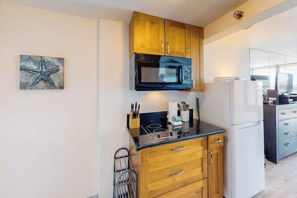 Built-in electric cooktop, microwave oven, custom wood cabinets, and full-size refrigerator. All ready for breakfast.