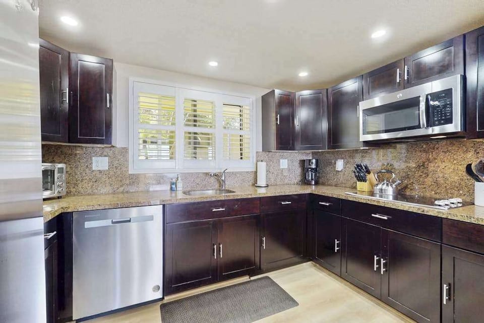 Chef's Kitchen Complete With Dark Wood Cabinets And Modern Appliances