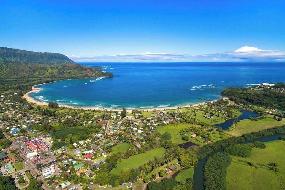 Panoramic surroundings feature verdant hills, tropical foliage, and distant coastlines