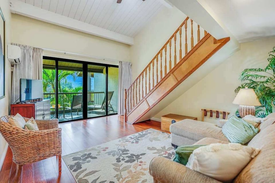 Open living room features staircase, balcony doors, and comfortable seating