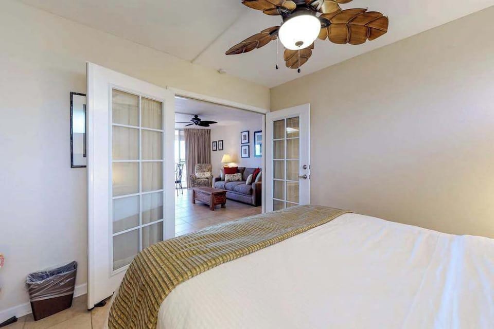 Bedroom, featuring a king bed, French doors, and a palm leaf fan.