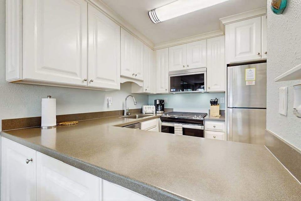 Cozy kitchen with everything you need for home-cooked meals, opening to the dining and living areas with abundant natural light from the sliding doors to the lanai.