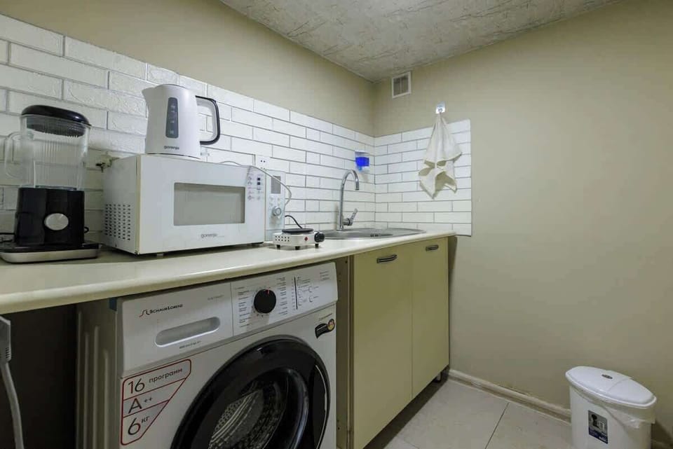 Compact kitchenette with washer, microwave, and coffee station.