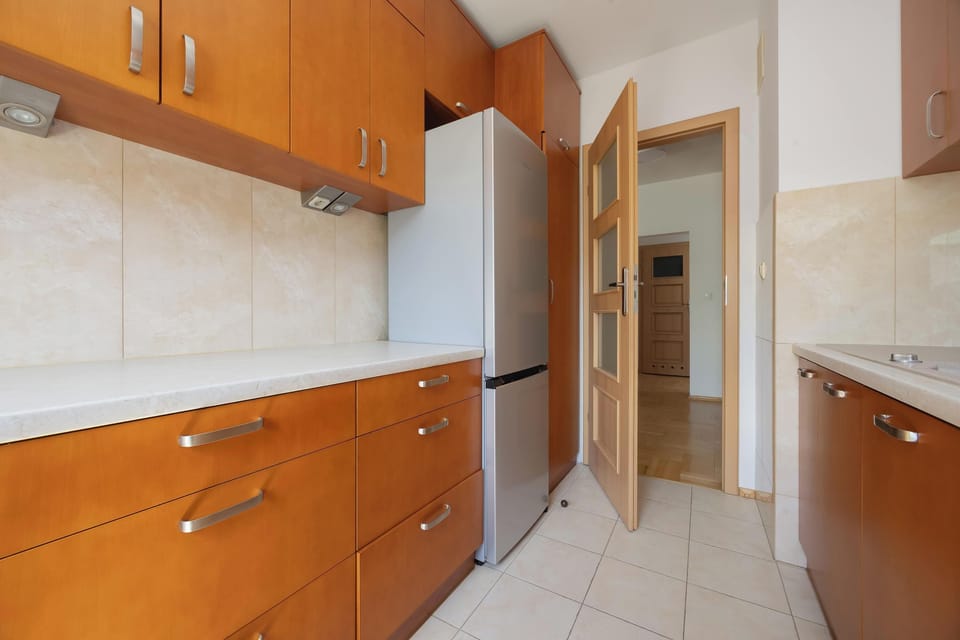 A bright kitchen with wooden cabinets and a spacious countertop. The layout offers plenty of storage and workspace.