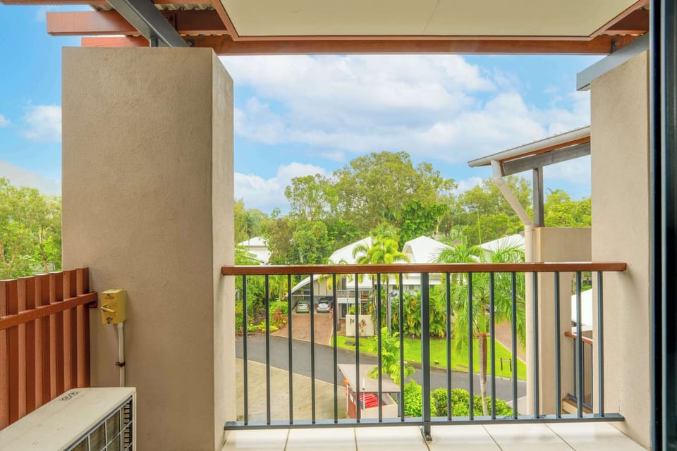 Enjoy fresh air from the primary bedroom balcony, where elevated leafy views offer a peaceful start before heading to the beach.