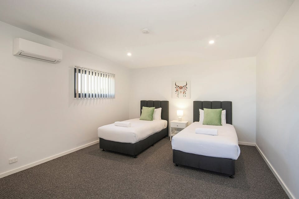 Bright twin bedroom with A/C, soft carpet, and clean modern styling