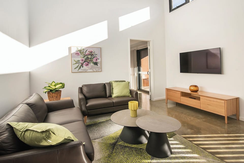 Sun-filled modern lounge with high ceilings, TV, and stylish seating