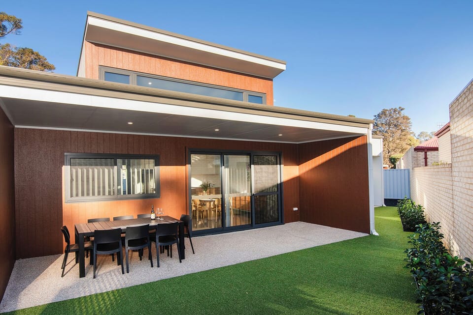 Covered alfresco patio with dining area and easy-care private yard
