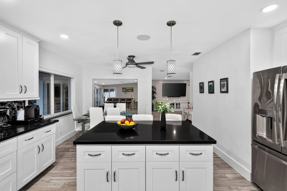 Modern kitchen with a large island, sleek black countertops, and open flow to the dining and living areas.