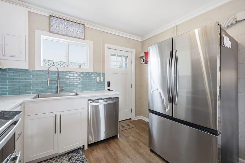 Your bright, beachy kitchen welcomes you with coastal charm—soft blues, gleaming appliances, and warm wood floors make cooking feel like a vacation in itself.