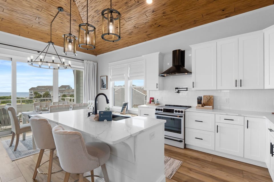 Picture yourself preparing meals in this bright, modern kitchen with stunning sea views. The open layout flows seamlessly to a waterfront balcony, inviting you to enjoy coastal breezes while cooking or gathering around the spacious island.