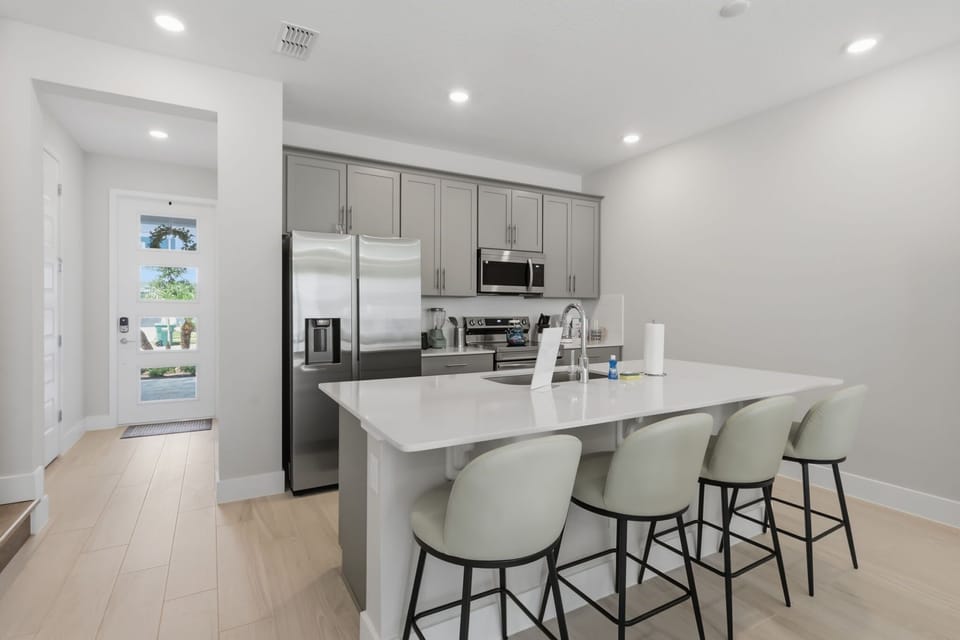 Modern kitchen with quartz countertops, stainless steel appliances, and seating for four at the island.