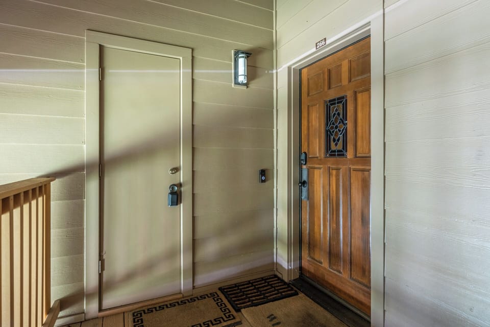 The welcoming entrance features a distinctive wooden door with decorative glass detailing and classic outdoor lighting. A covered porch area provides shelter as guests arrive at unit 306.